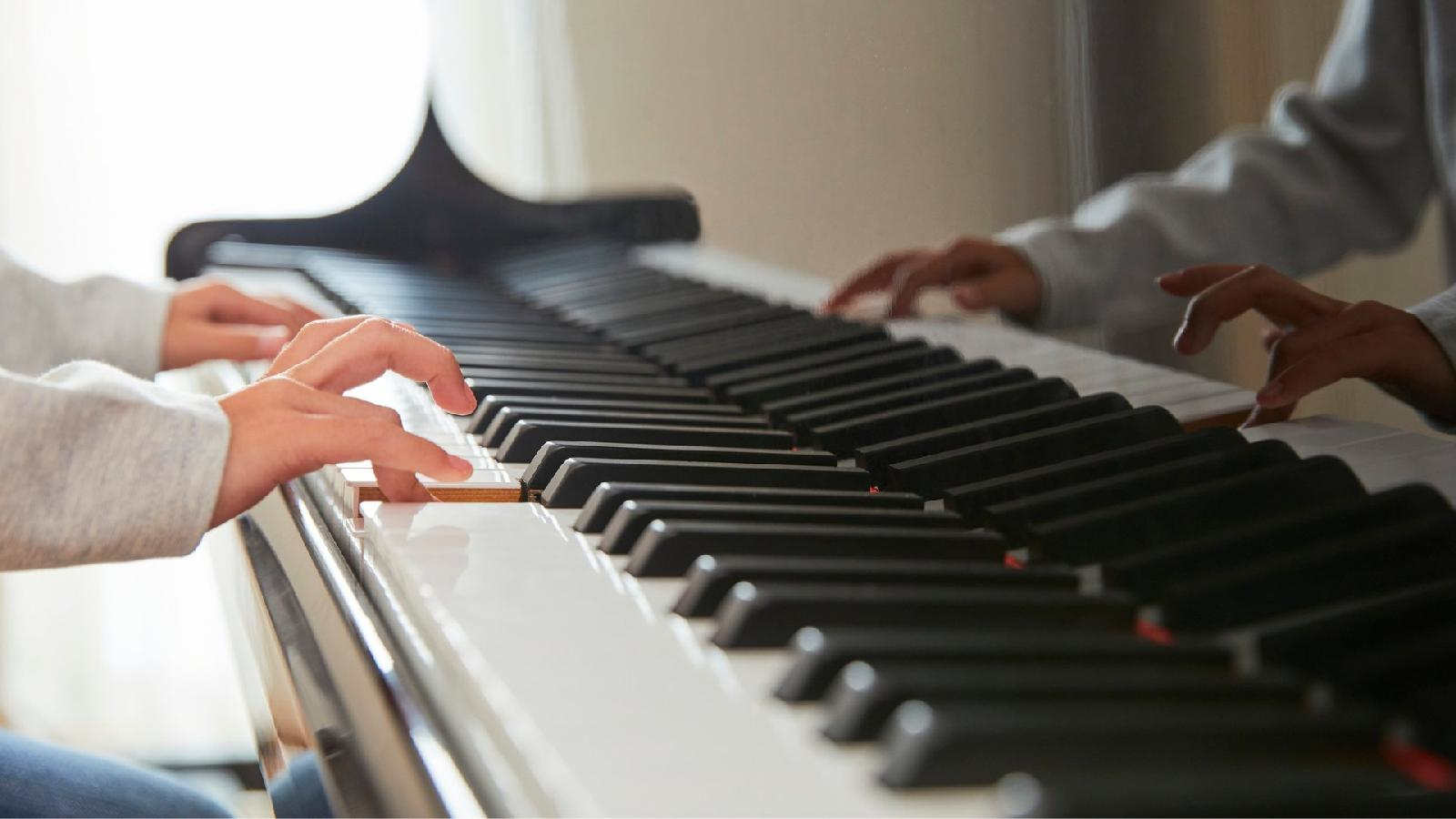 Élève débutant pratiquant le piano lors d'un cours à domicile avec un professeur Allegro Musique