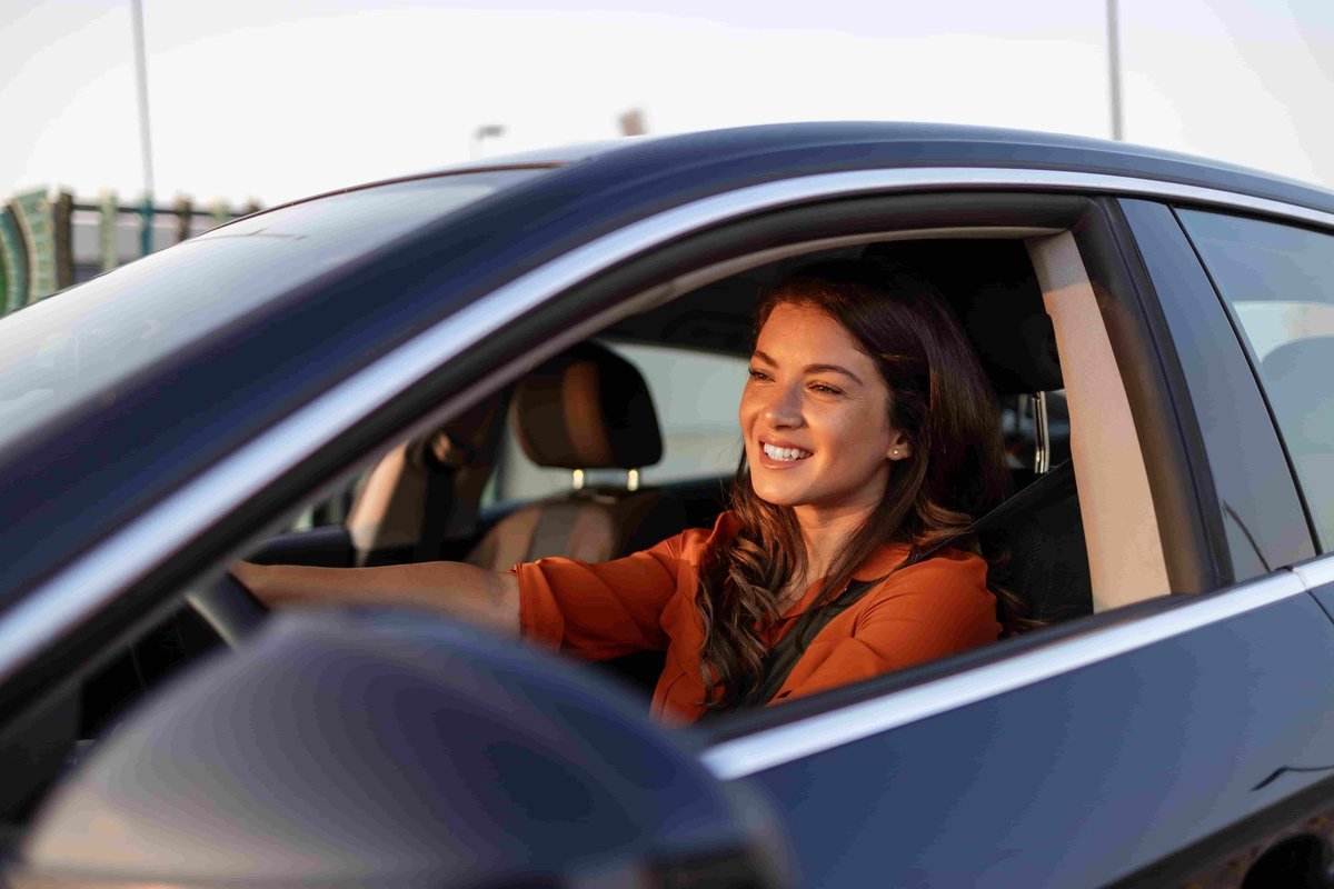 Femme souriante au volant d'une voiture pendant les vacances