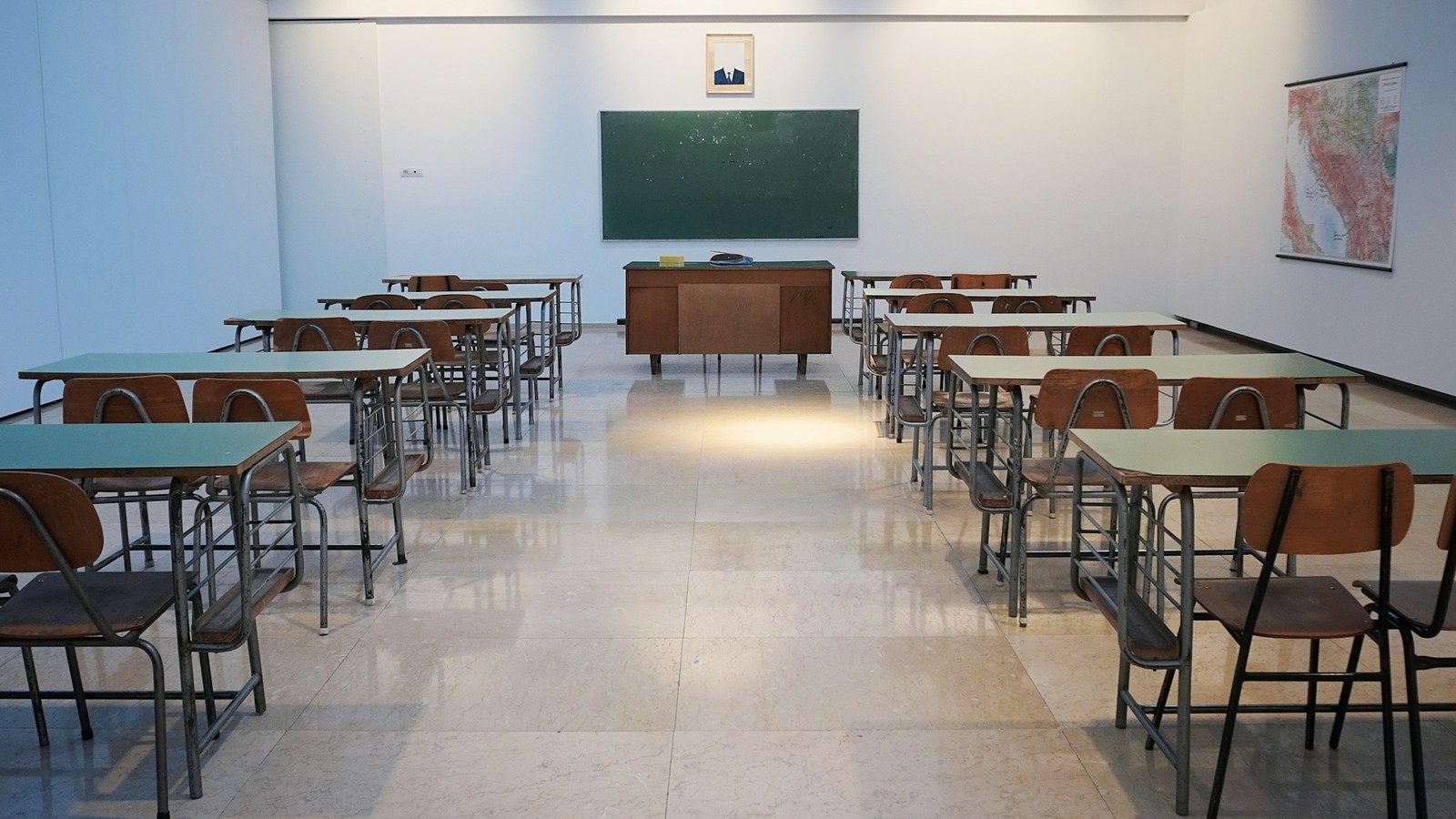 Salle de classe vide avec rangées de pupitres en bois et tableau noir