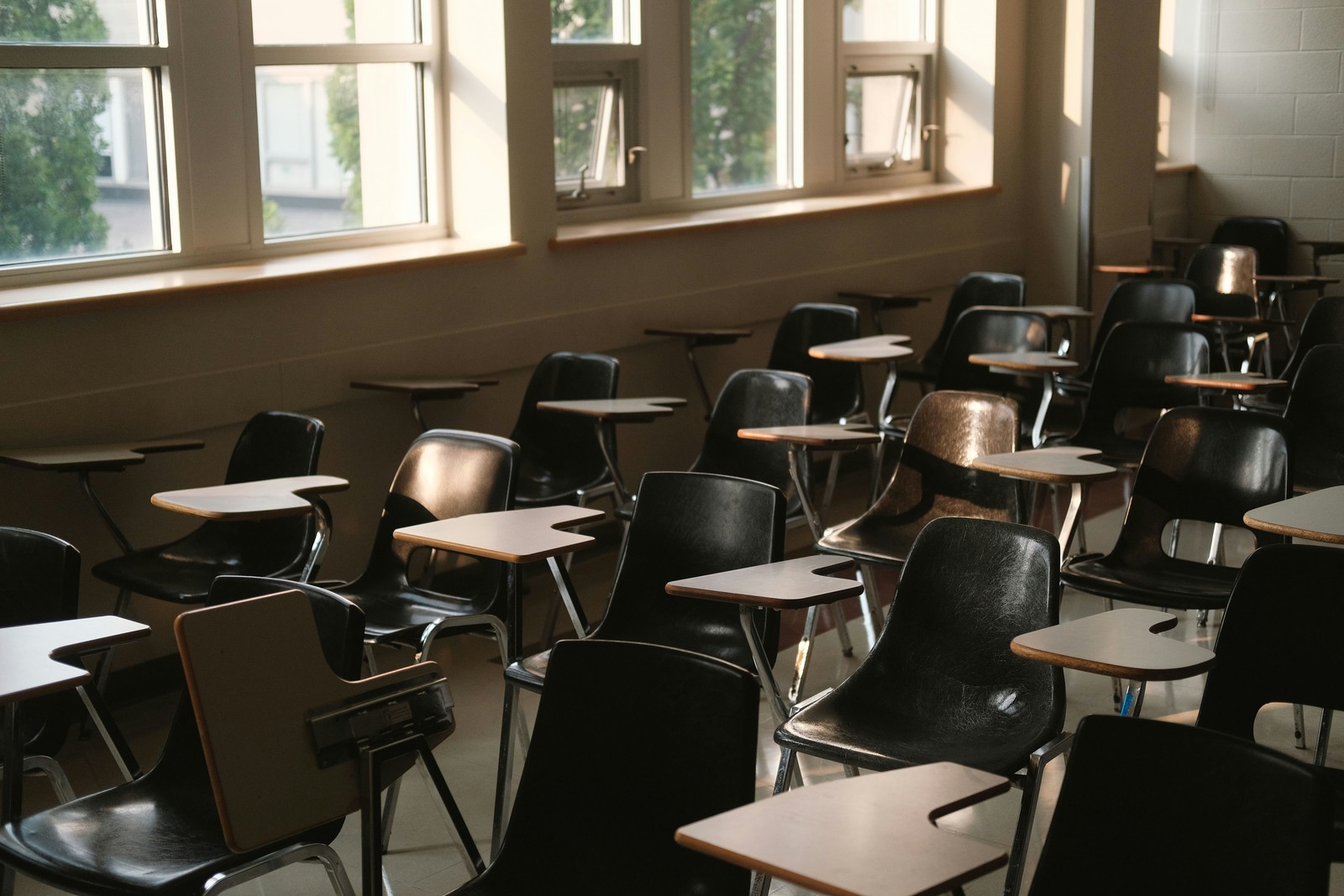 Rangées de bureaux et chaises vides dans une salle de classe éclairée par la lumière naturelle