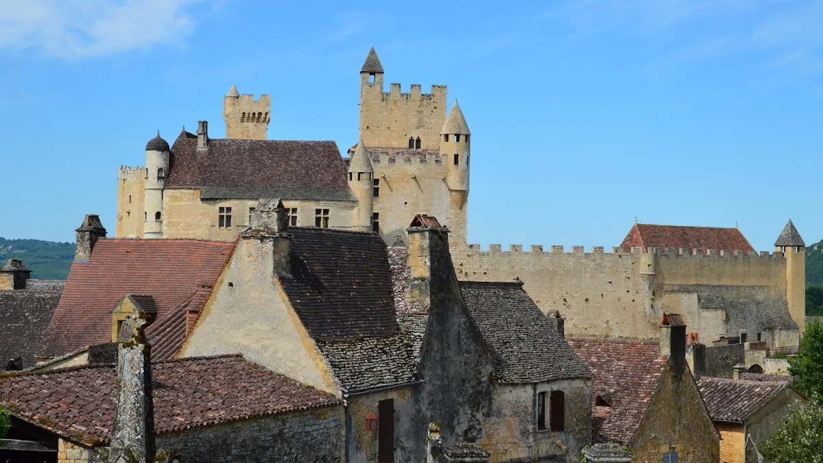 Majestic view of Beynac Castle's ancient architecture under a bright blue sky in France.