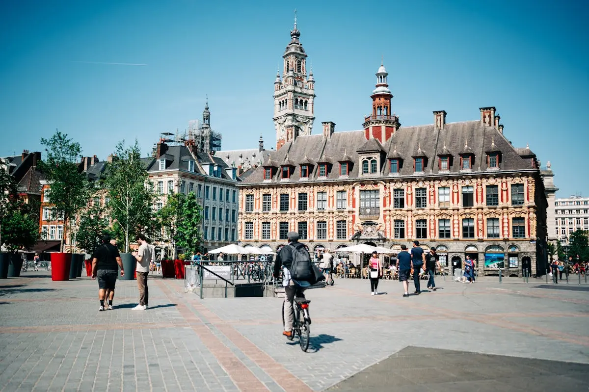 Lively city square in Lille with historic architecture and people enjoying a sunny day.