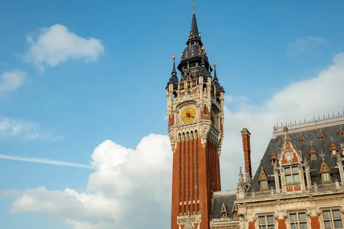 Stunning view of the iconic Belfry of Calais against a blue sky, showcasing neo-Gothic architecture.