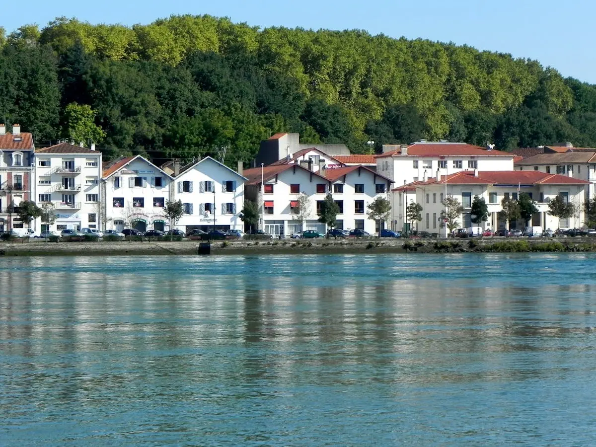 Scenic view of riverside architecture in Bayona, Nueva Aquitania, France, under clear summer skies.