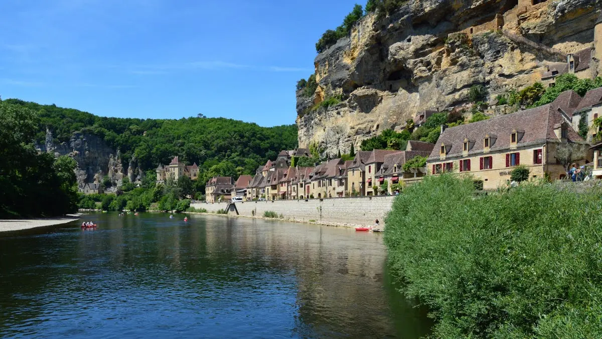 Picturesque village by a river with stone houses and cliffs in France.