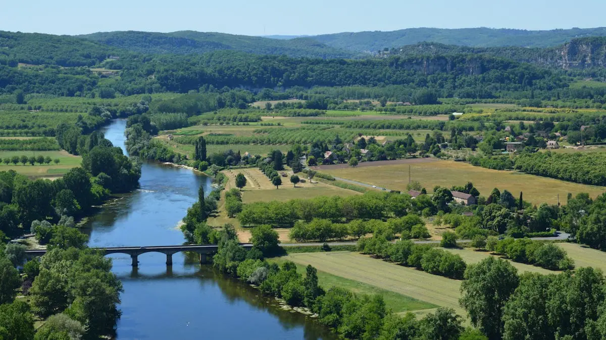 A scenic view of the Dordogne River flowing through the lush French countryside in summer.