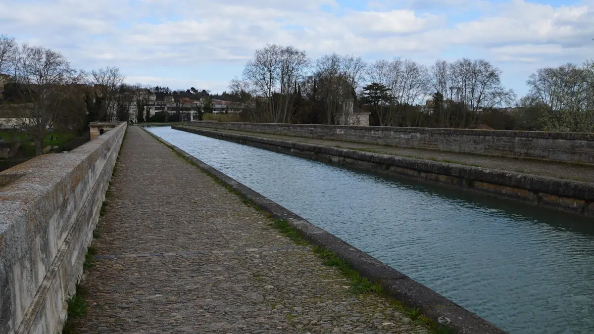 Picturesque view of the Canal du Midi aqueduct in Béziers, showcasing serene water and rustic stonework.