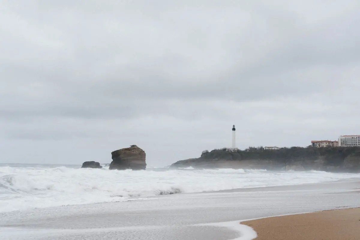 Surfeur sur la plage de Biarritz avec le phare en arrière-plan