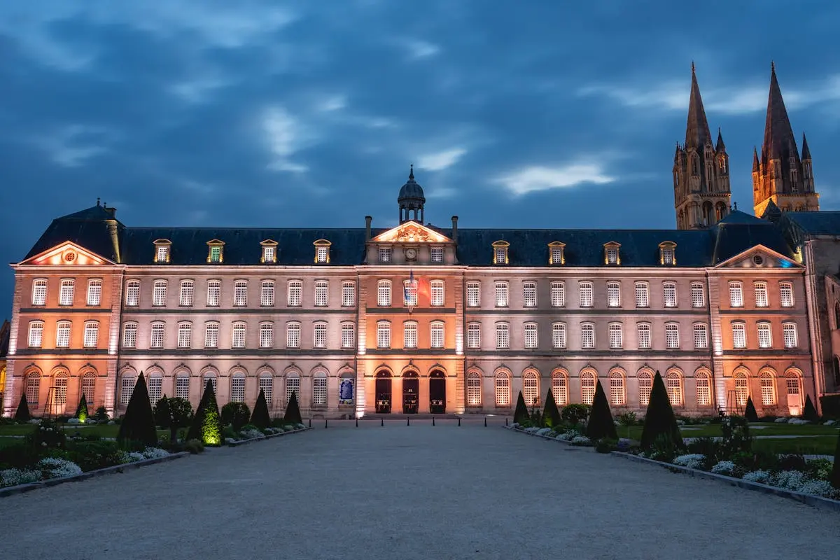 Façade illuminée d'abbaye au crépuscule à Caen