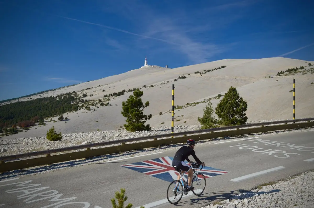 Cyclist climbing Mont Ventoux in Vaucluse, France, under clear blue skies, capturing the essence of Tour de France.