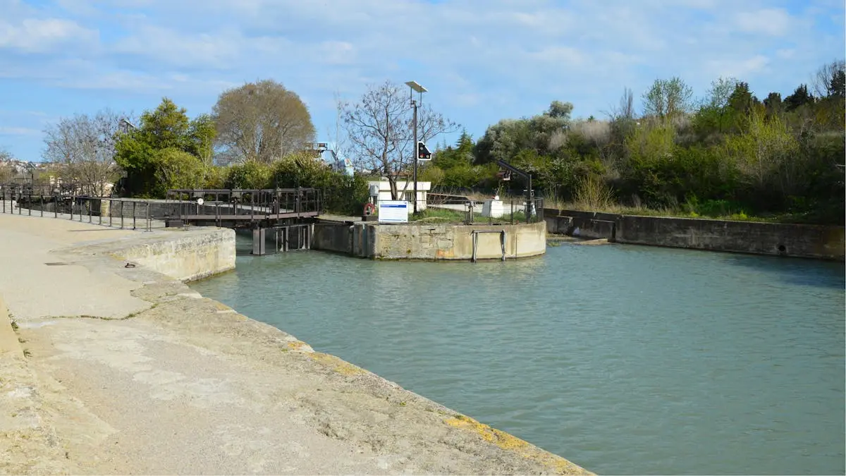 Scenic view of canal locks in Béziers, France with greenery and blue sky on a sunny day.