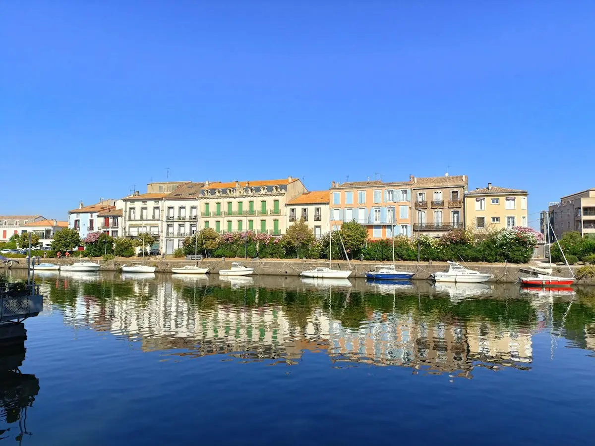 Scenic view of colorful buildings and boats along the waterfront in Agde, France.