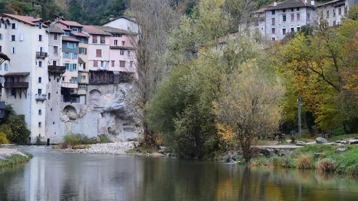 Picturesque riverside view of a quaint village with historic buildings and autumn scenery.