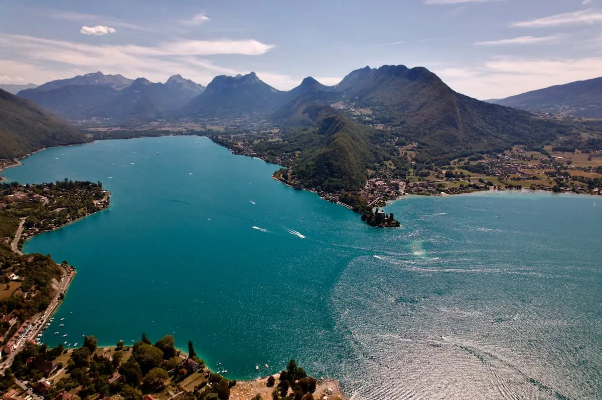 A breathtaking aerial photograph of Lake Annecy with surrounding mountains in Auvergne-Rhône-Alpes, France.
