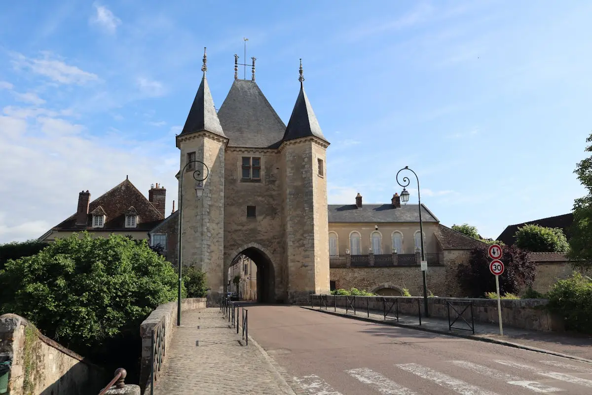 A view of an ancient stone gate tower with gothic architecture under a clear summer sky.