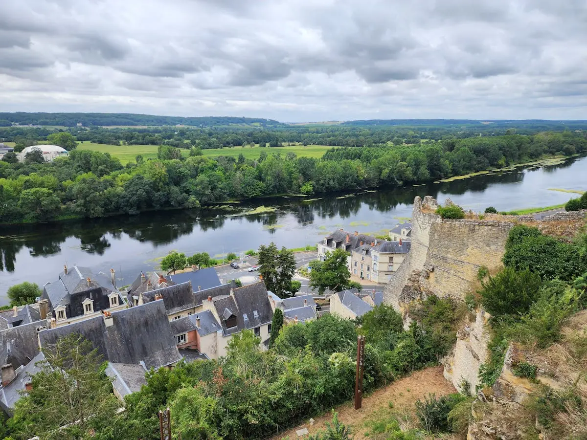 Aerial view of Chinon, France showing castle ruins, river, and lush greenery.