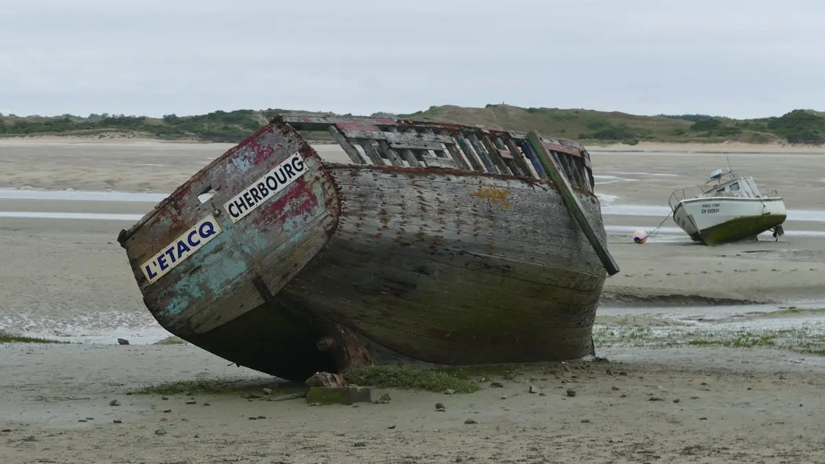 Old wooden boats stranded on sandy shore at Port-Bail-sur-Mer, France.