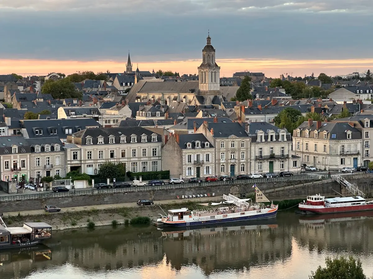 Historic cityscape of Angers, France, featuring charming architecture along the river at sunset.