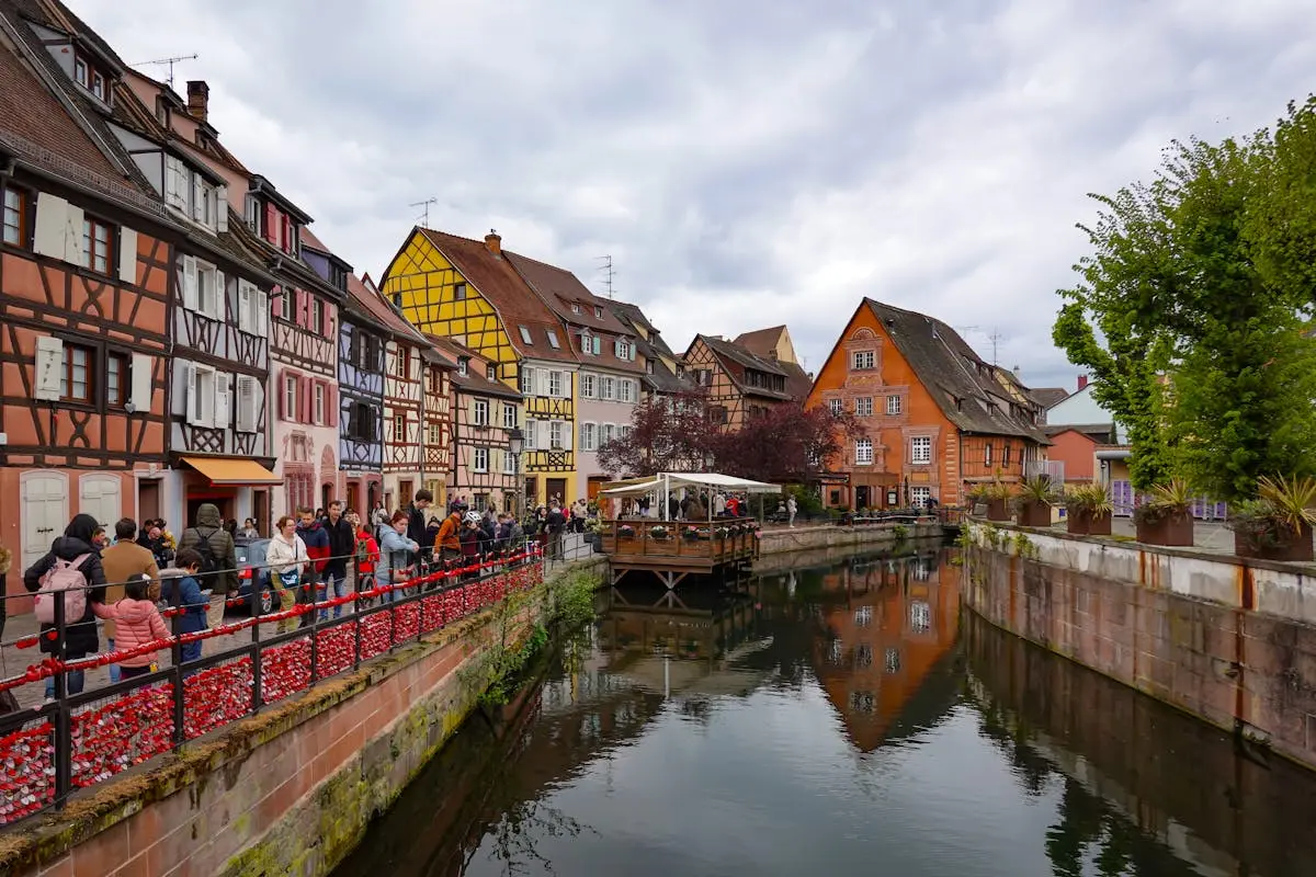 Picturesque canal scene in Colmar, France with vibrant medieval half-timbered buildings.