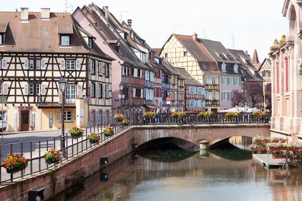 Scenic view of Colmar's half-timbered houses and picturesque bridge over a peaceful canal.