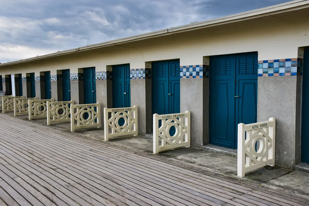 Charming beach cabins with blue doors on Deauville promenade, Normandy, France.