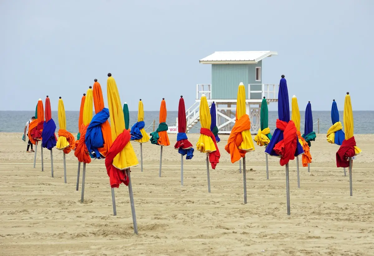 Vibrant beach umbrellas at Deauville beach in Normandie, France, with a tranquil seascape.