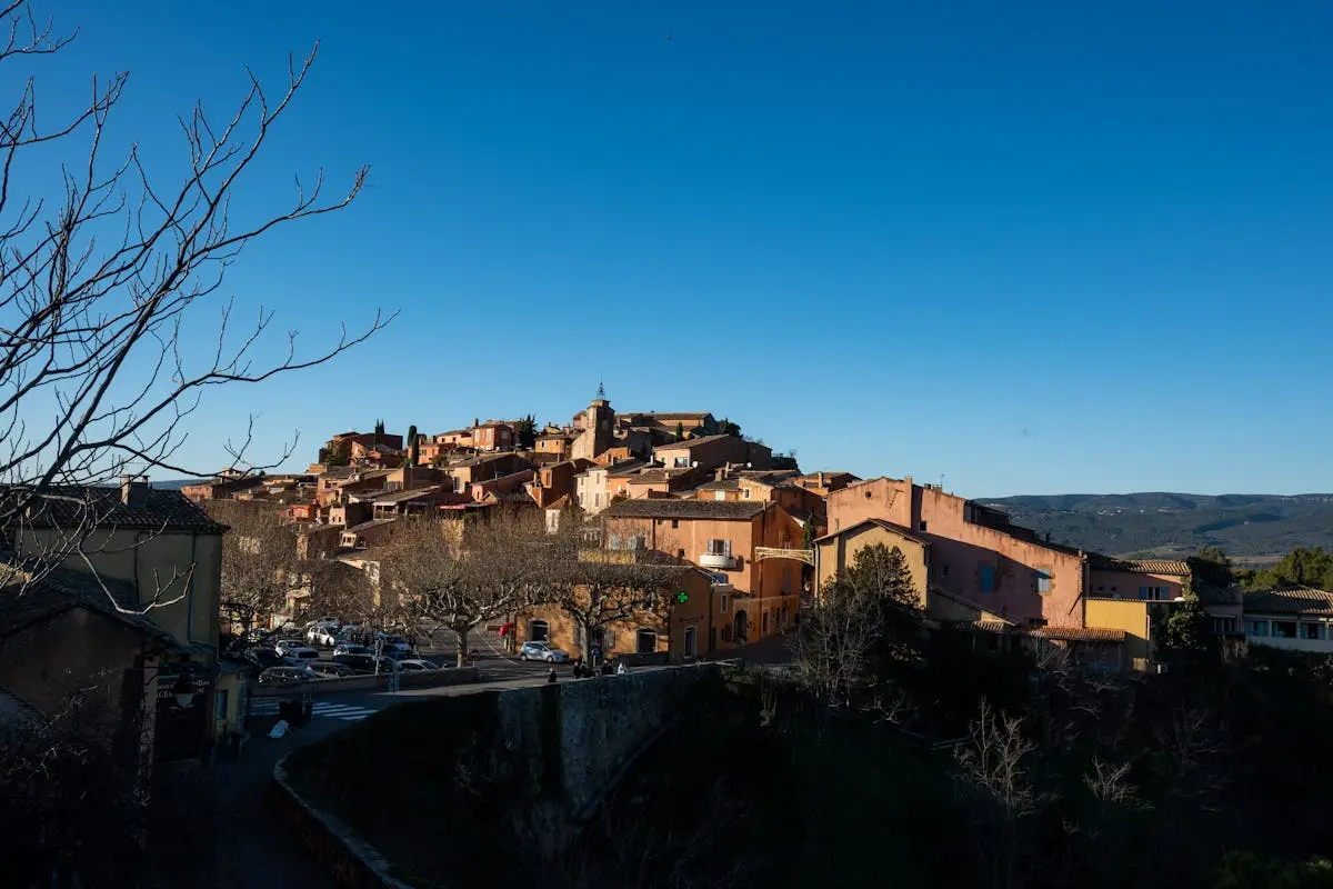 Picturesque view of Roussillon village in Provence with traditional ochre-colored buildings under a clear blue sky.