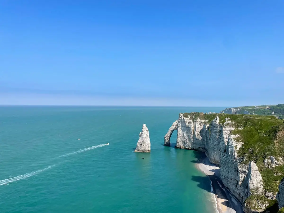 Breathtaking view of Étretat's iconic chalk cliffs and blue sea under a clear sky in Normandie, France.