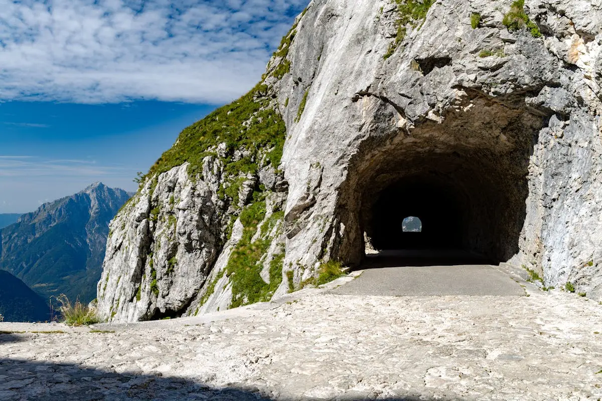 Scenic view of a mountain tunnel with rugged rocks and blue sky in Slovenia.
