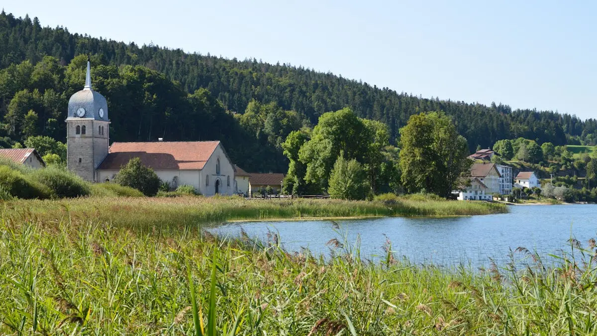 Tranquil view of a rural church and lake in Bourgogne-Franche-Comté, France.