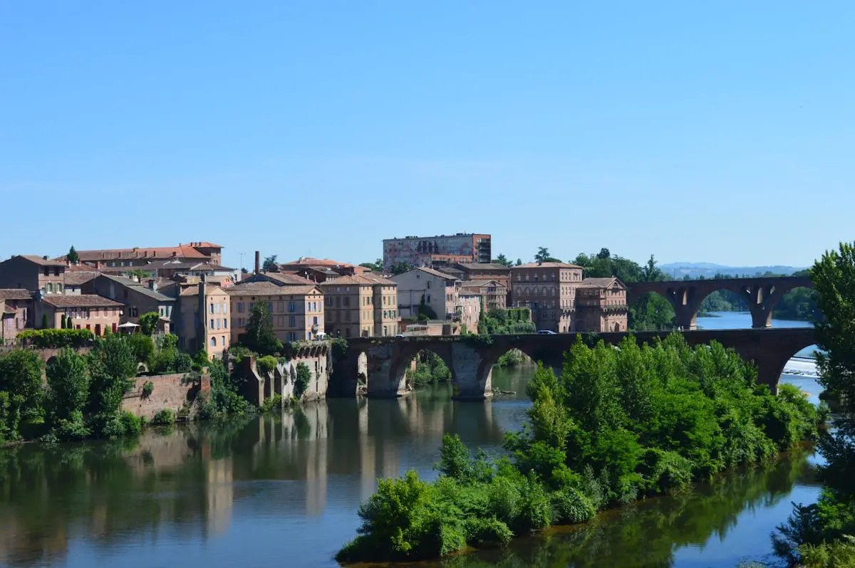 Charming view of Albi's old town with a stone bridge reflecting in the river.