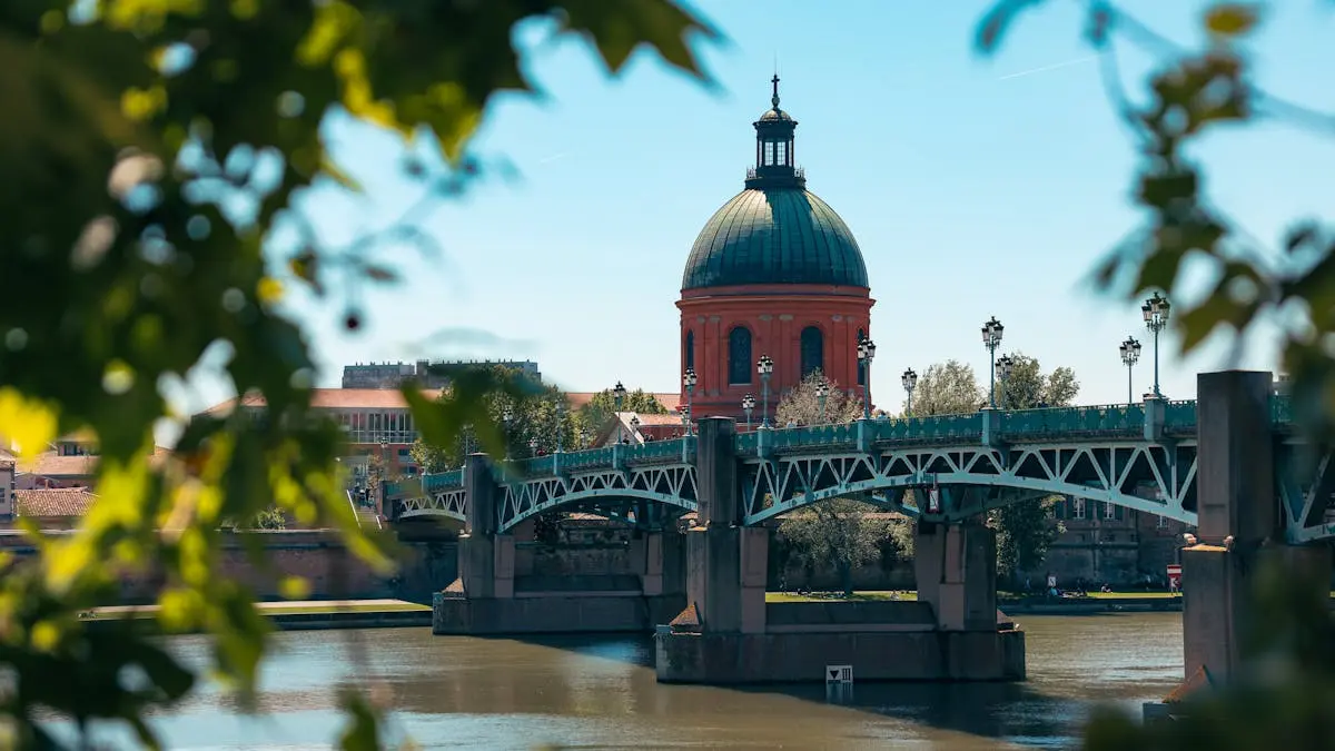 Scenic view of Pont Saint-Pierre and red dome in Toulouse, France framed by leaves.