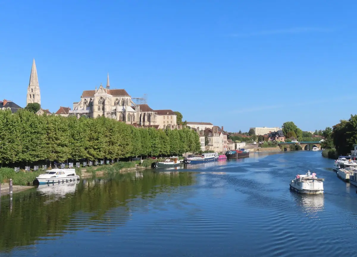 Stunning view of Yonne River with boats and Auxerre Cathedral in Bourgogne, France.