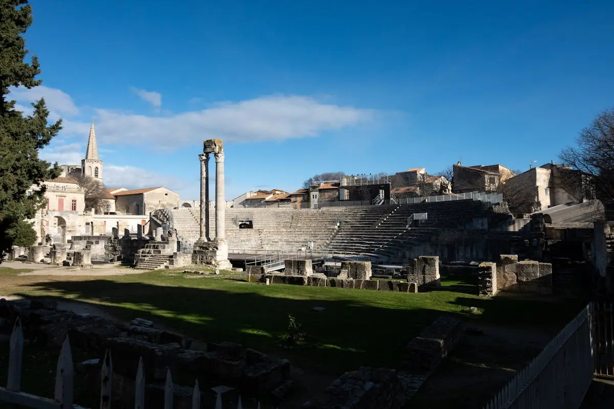 Historic Roman amphitheatre in Arles, France, showcasing ancient architecture under a bright sky.