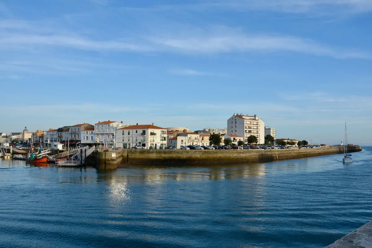 Beautiful harbor scene in Les Sables-d'Olonne, France with calm waters and buildings.