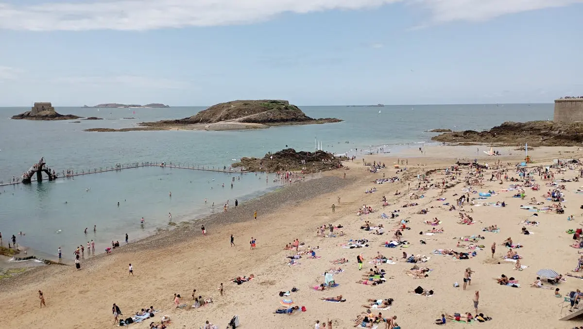 A sunny day at Saint-Malo beach with tourists enjoying the seaside views.