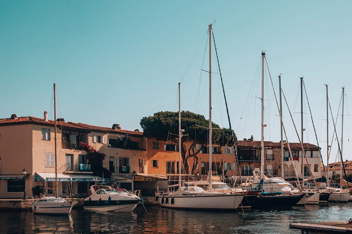 Quaint harbor scene with docked sailboats in Grimaud, France, featuring charming Mediterranean architecture.