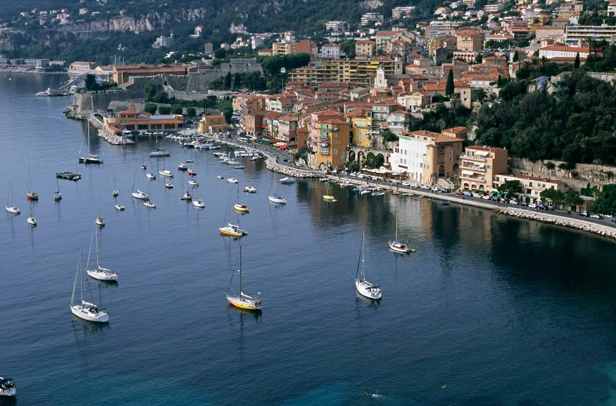 A scenic aerial view of Villefranche-sur-Mer's harbor with vibrant buildings and moored sailboats, capturing coastal charm.