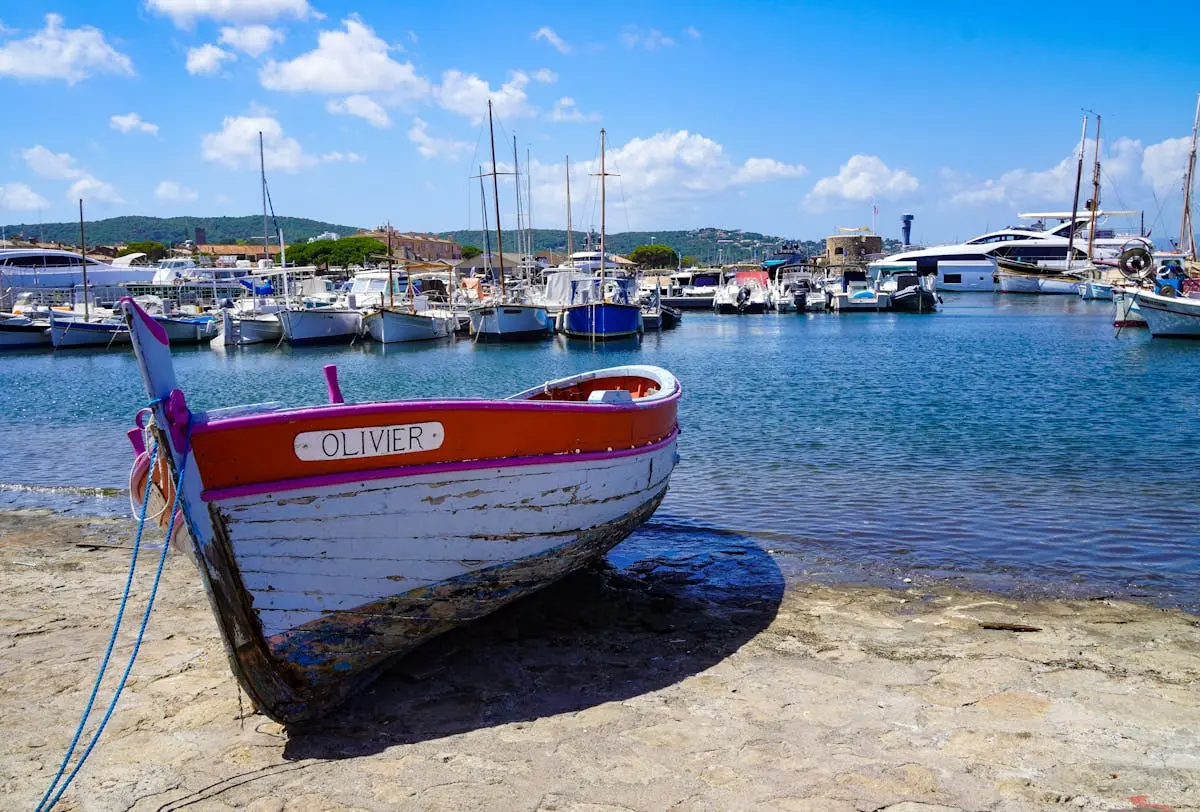 A vibrant scene of traditional wooden boats docked in the charming harbor of Saint-Tropez under a clear blue sky.