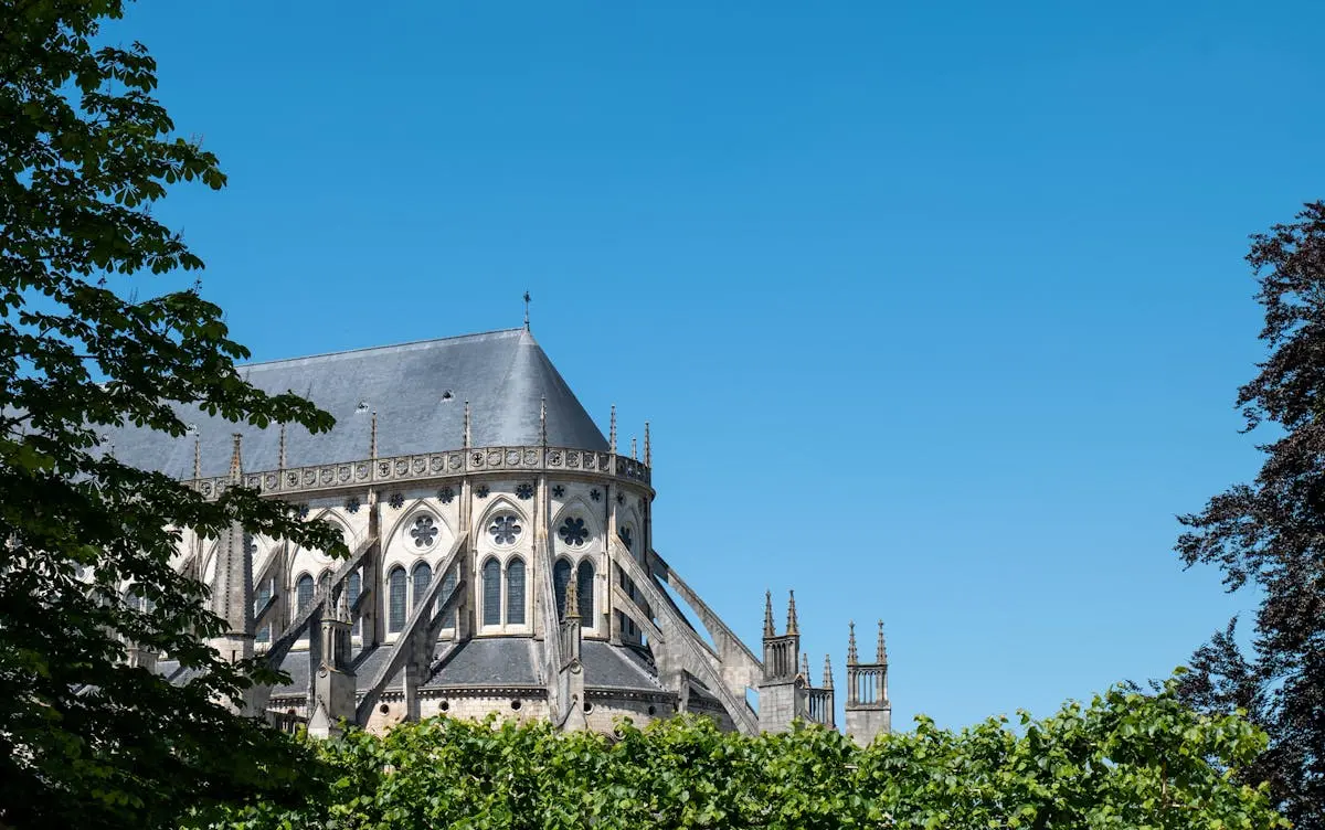 Stunning Gothic cathedral with lush greenery and bright blue sky, evoking historical elegance and tranquility.