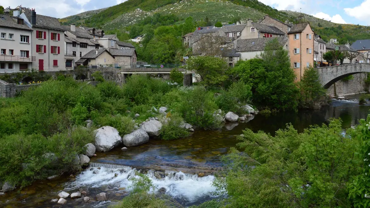 Charming village of Pont de Montvert in Occitanie, France with lush greenery and a river.