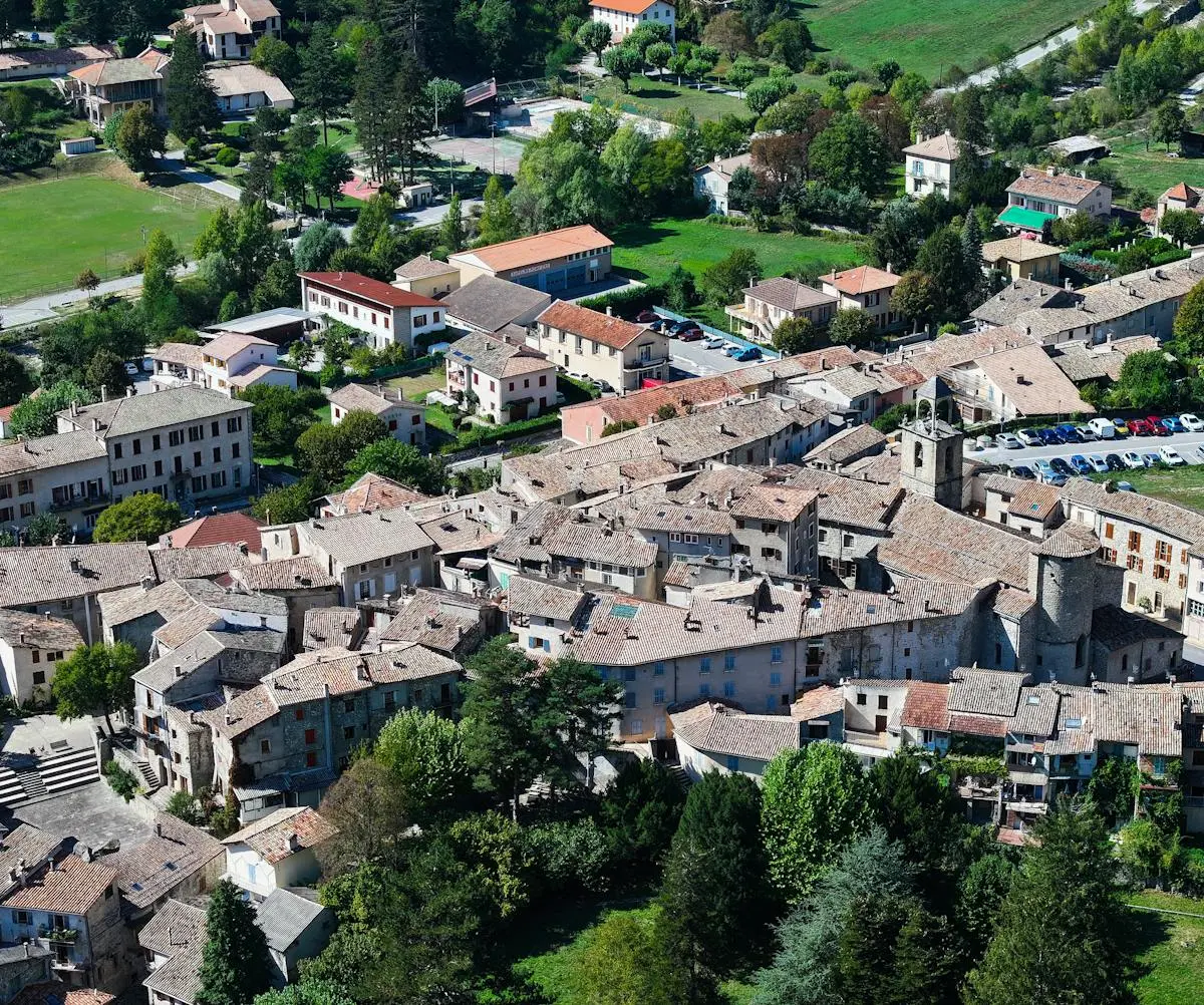 Explore the charming terracotta rooftops and lush greenery of Annot, a picturesque village in Provence, France, captured from above.