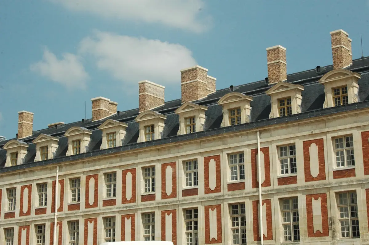 A detailed facade of a historic French building with blue sky background, showcasing classic architecture.