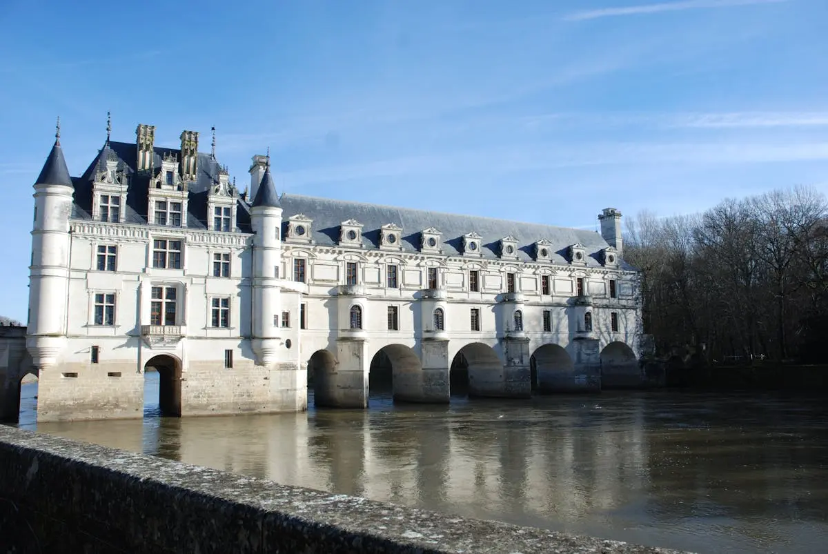 Stunning view of Château de Chenonceau spanning the River Cher under a clear blue sky.